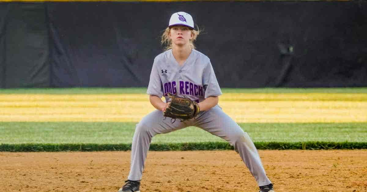 A high school baseball player standing ready on a sunny baseball field during a game