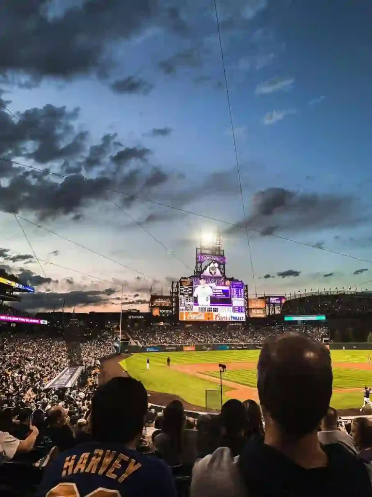 Baseball box seats at a packed stadium with fans under a clear sky