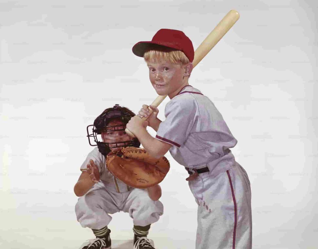 Two young boys holding baseball bats, showing how many players are on a baseball team from MLB to Little League