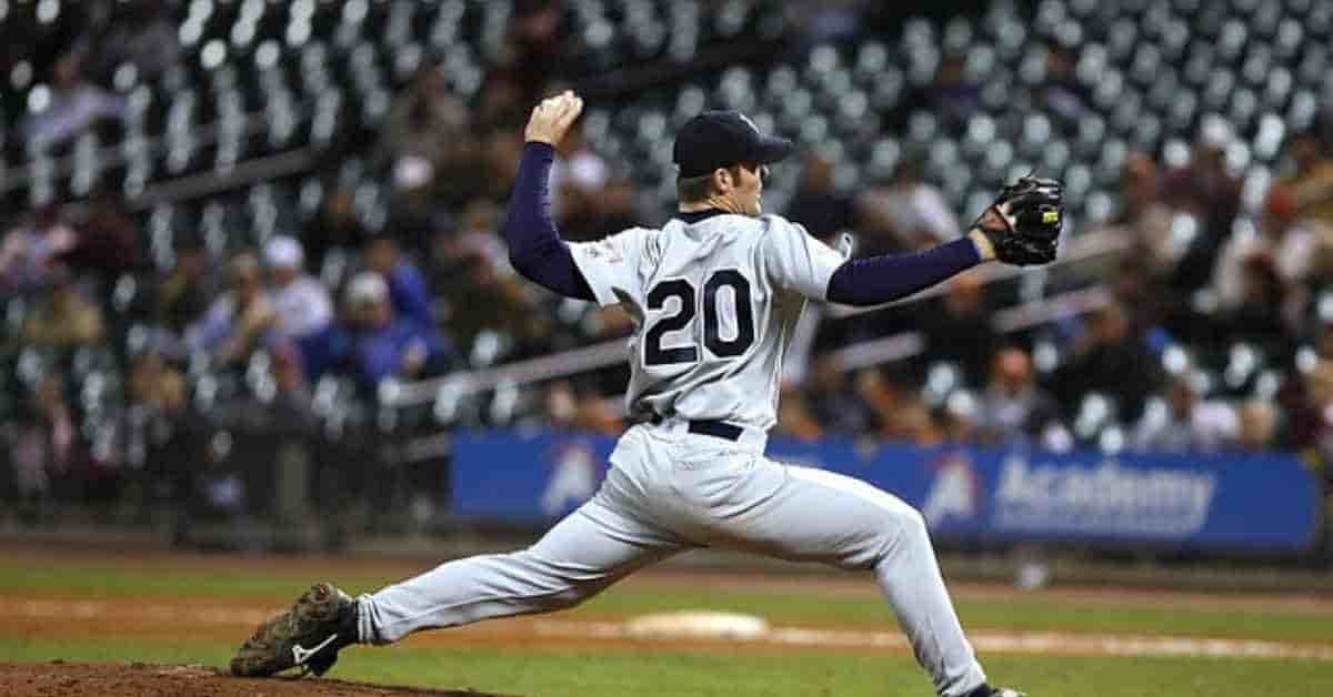 A baseball player in white baseball pants pitching a ball on the field