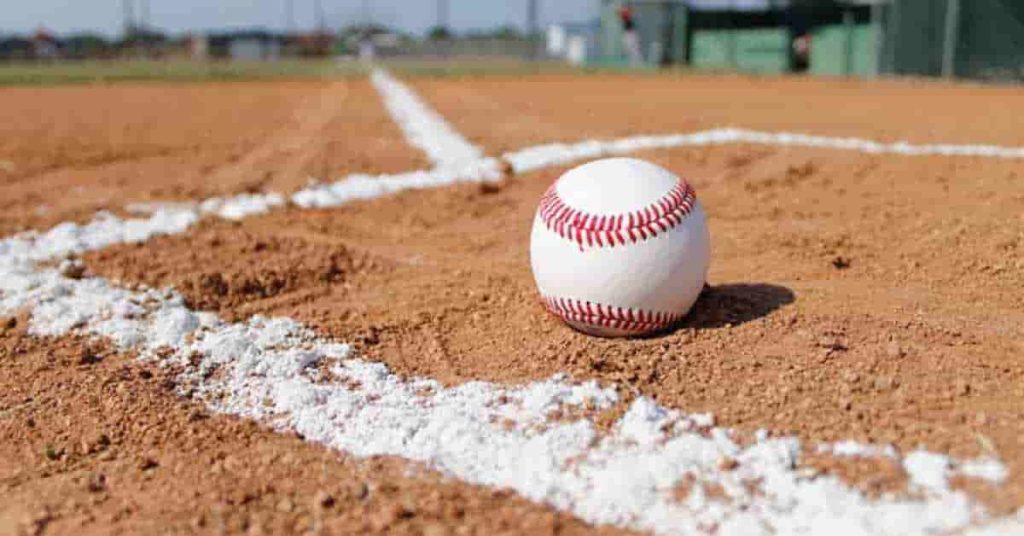 A baseball is sitting on a baseball field, waiting for a hot bat in baseball to make contact.