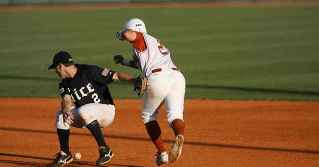 How Long Do Baseball Games Last? _ A Guide 2 A player in a white uniform attempts to steal a base while a player in a black uniform prepares to tag him on a baseball field during a typical play that fans might see when wondering how long is baseball games.