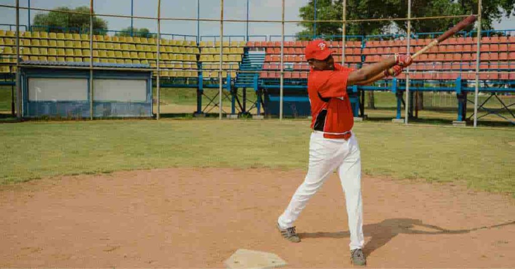 A semi-pro baseball player swinging a bat on a field