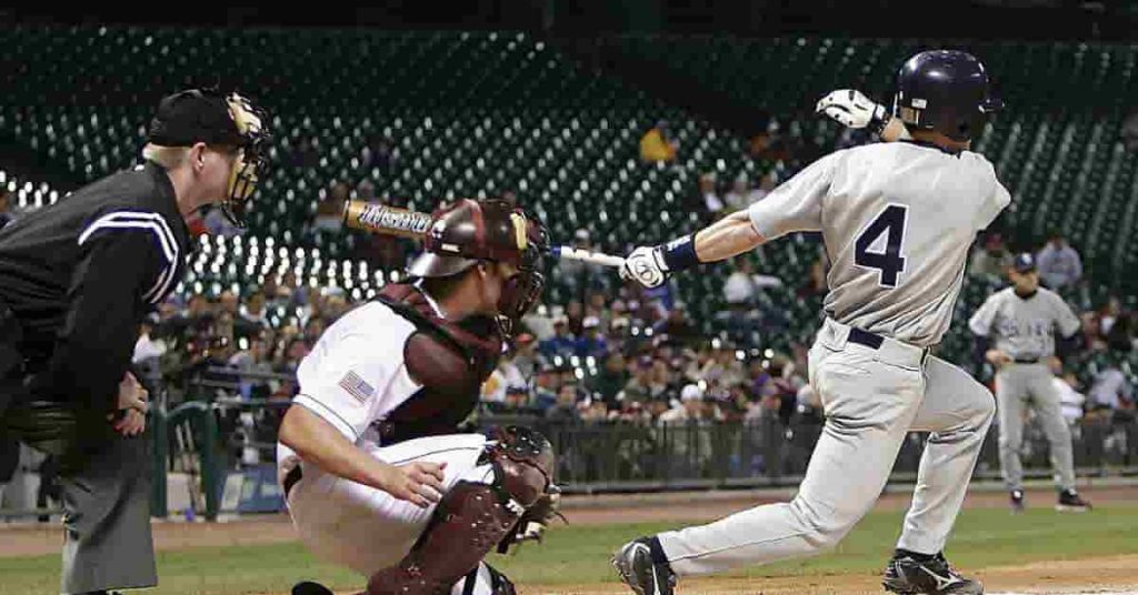 A wooden baseball bat with a specific bat drop alongside a baseball on a green field, illustrating the concept of bat drop in baseball