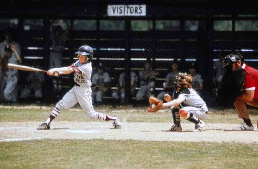 A semi-pro baseball player swinging a bat at a ball