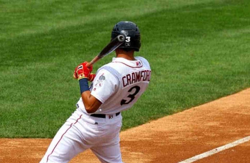 A baseball player holding a bat on a field, representing the home team sit in baseball.