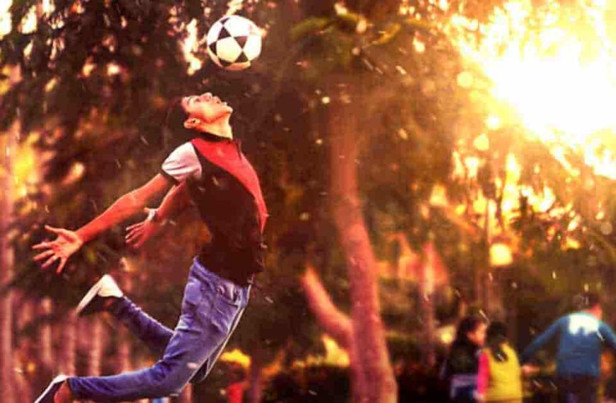 A man jumping in the air to catch a soccer ball, illustrating athleticism in football.