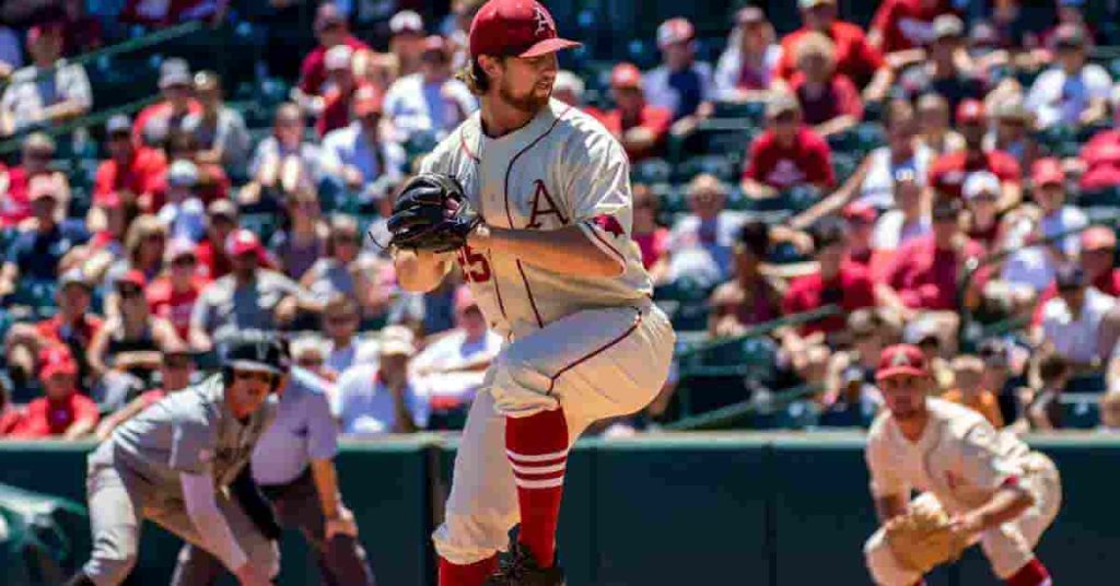 A baseball player wearing baseball cleats pitches a ball on top of a field