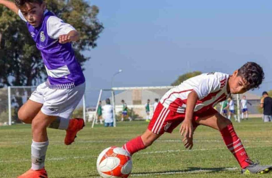 A couple of young men kicking a soccer ball around a field, showcasing how long a soccer match lasts.