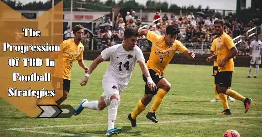 A group of young men playing soccer on a grassy field, with players in different colored jerseys, running and dribbling the ball. The game details are tbd in football.