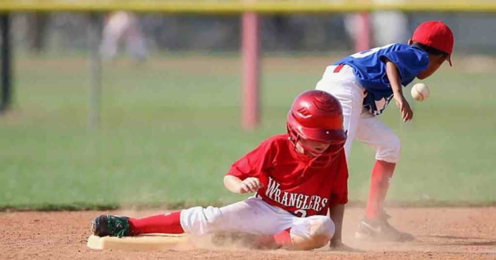 A young boy sliding into a base during a baseball game, aspiring to one day find out how much do minor league baseball players make.