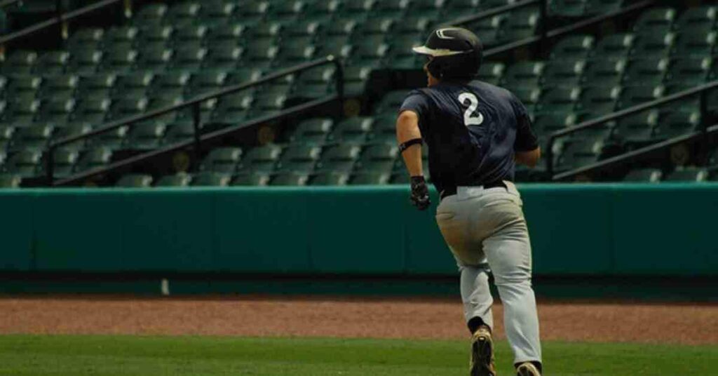 John Schneider coaching a baseball player running on a baseball field.