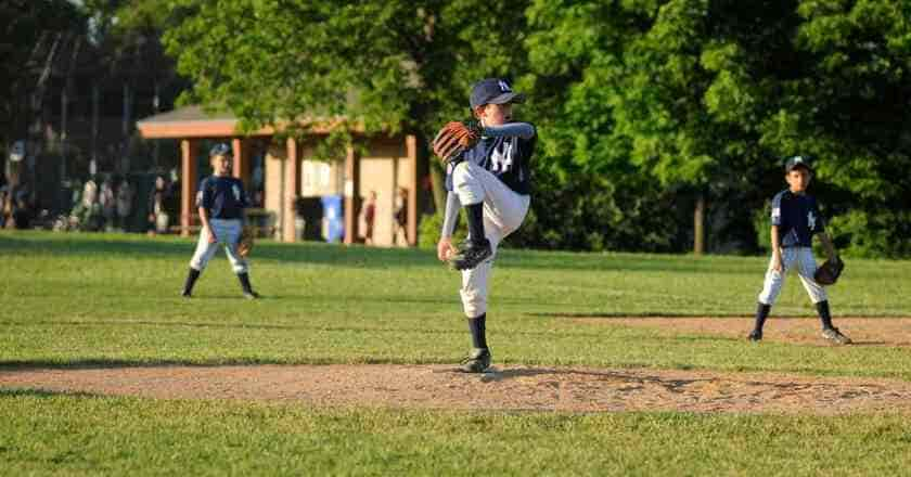 A baseball player pitching a ball on a field, aware of the impact bat rolling can have on the game.