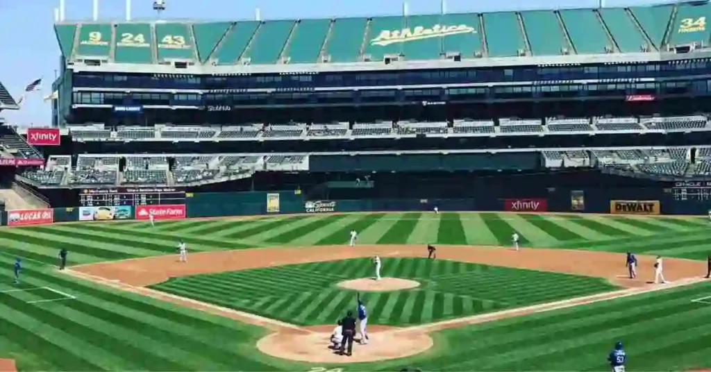 Baseball Terms and Their Importance 2 A sunny baseball game in Oakland's stadium features players on the field and empty seats in the stands, showcasing classic baseball terms in action. Green grass and crisp lines add to the scene.