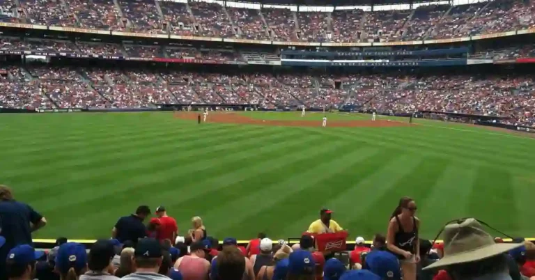 a crowd of people watching a baseball game, including some of the oldest players in action