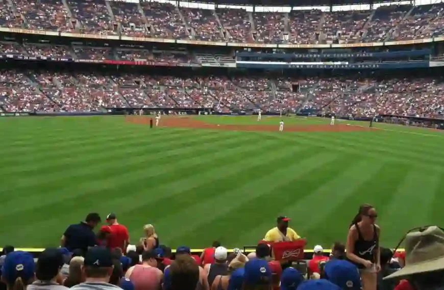 a crowd of people watching a baseball game, including some of the oldest players in action