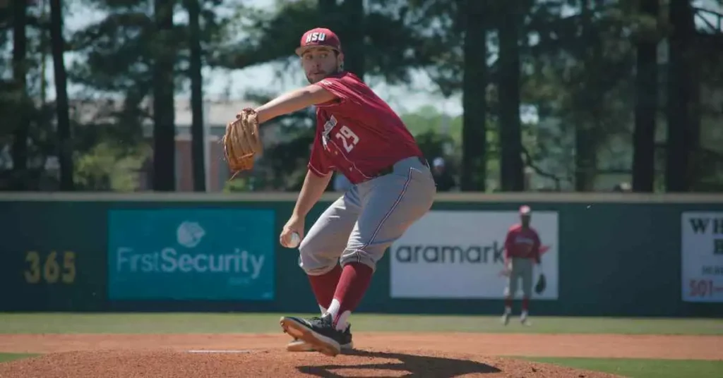 What Is Mercy Rule In Baseball-Understanding Baseball 2 A baseball player in a red jersey pitches on a sunny field, with a teammate in the background near the pitcher's mound, showcasing the concept of the mercy rule in baseball.