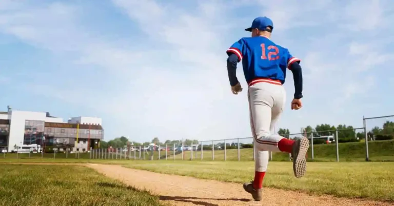 A young baseball player in a blue jersey with the number 12 runs along a dirt path, heading towards a baseball field under a blue sky, representing the World Baseball Classic.