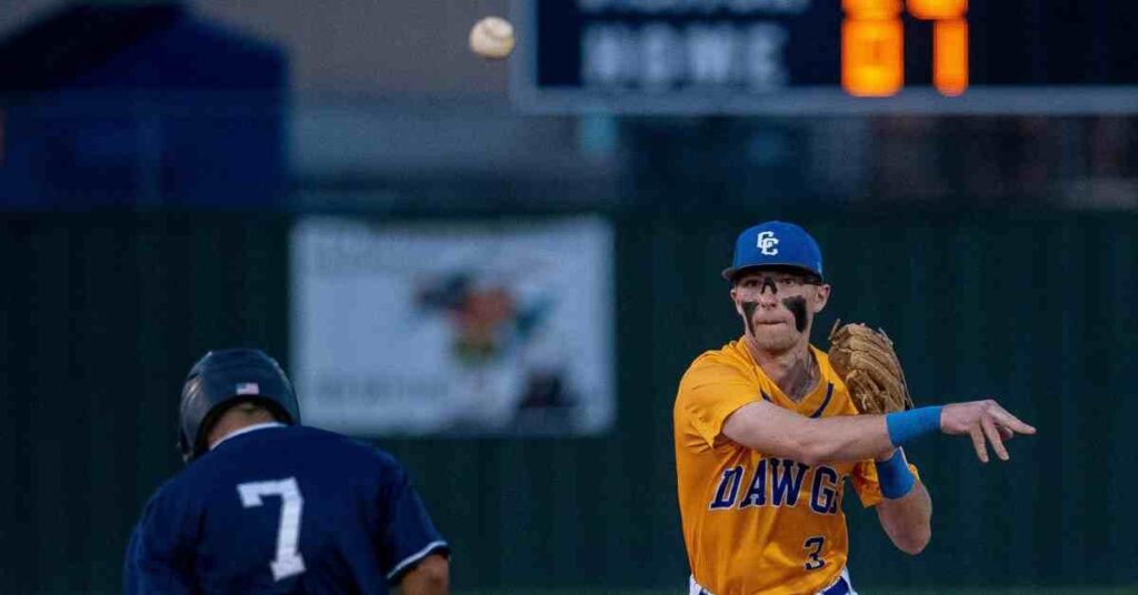 Who is Marcus Semien?A Closer Look at His Path, Career Stats, and Awards 2 Marcus Semien, a baseball player in a yellow jersey, throws the ball towards a player in a blue jersey, with a scoreboard showing the game score in the background.